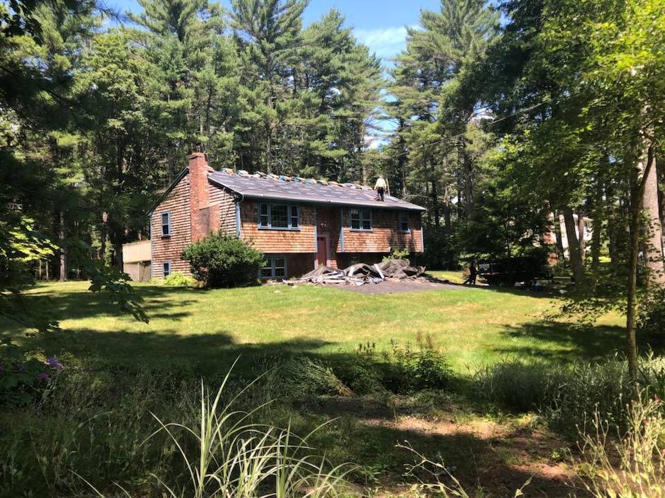Cedar-shingle South Shore MA home undergoing a roof replacement with a Jennifer Construction roofer working on the roof